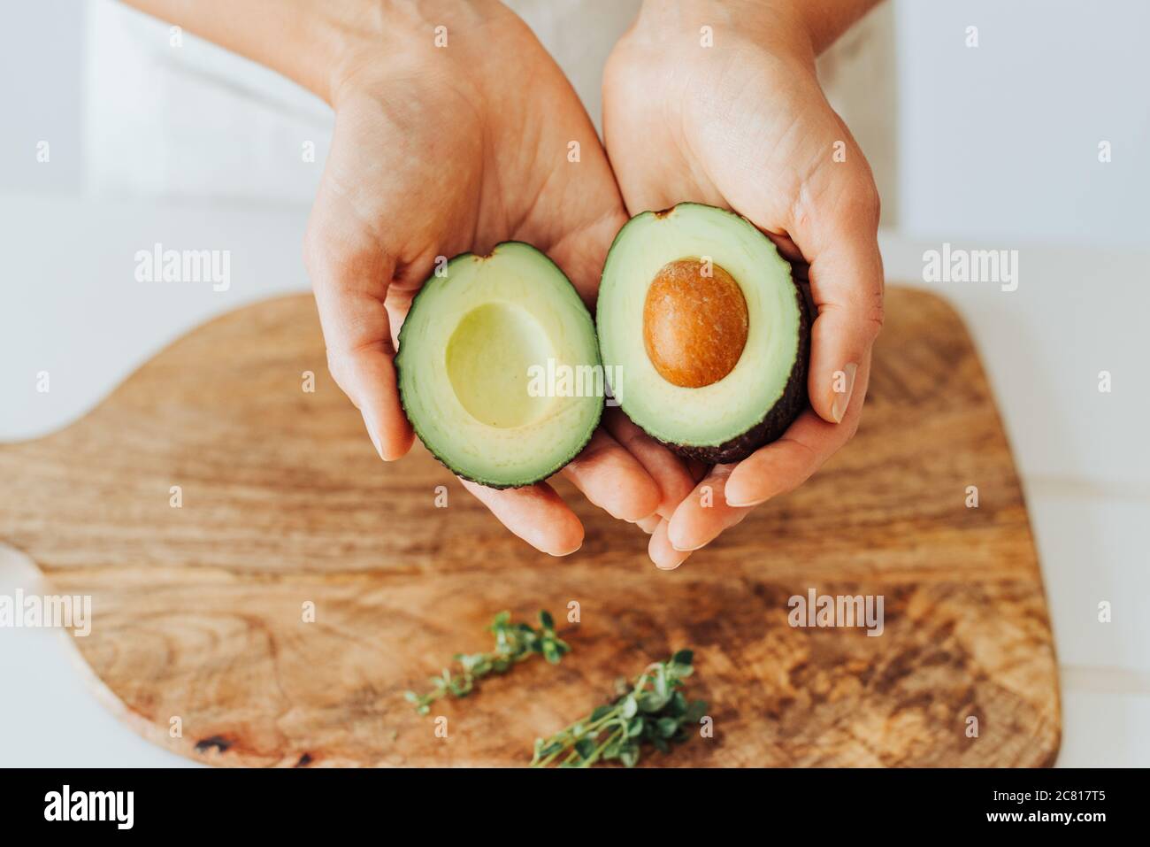 Primo piano di mani che tengono avocado fresco, fonte di grassi sani Foto Stock