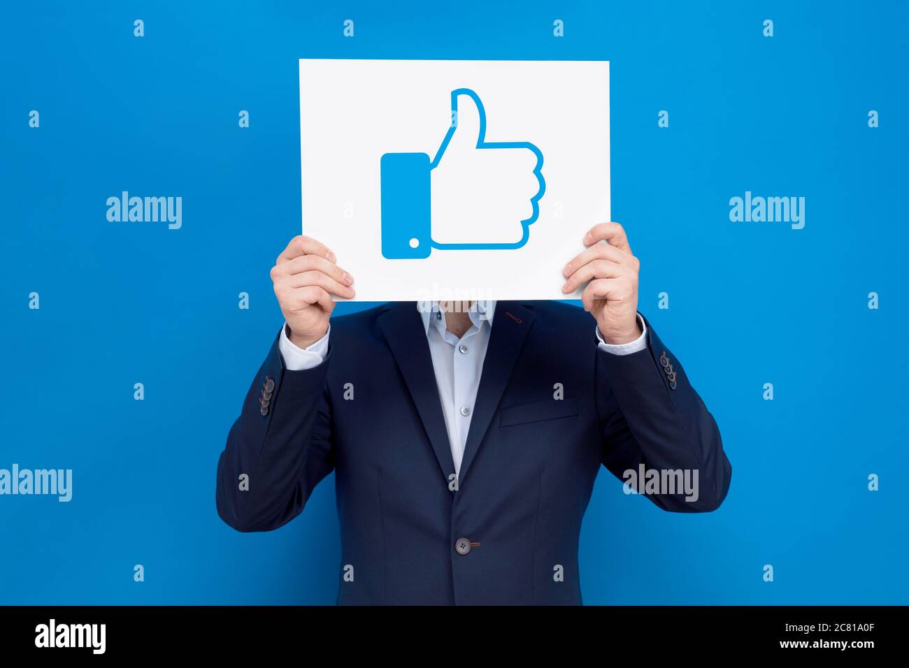Uomo d'affari copre il suo volto con lavagna bianca con il segno 'pollice su'. Concezione aziendale del marketing nei social media. Foto Stock