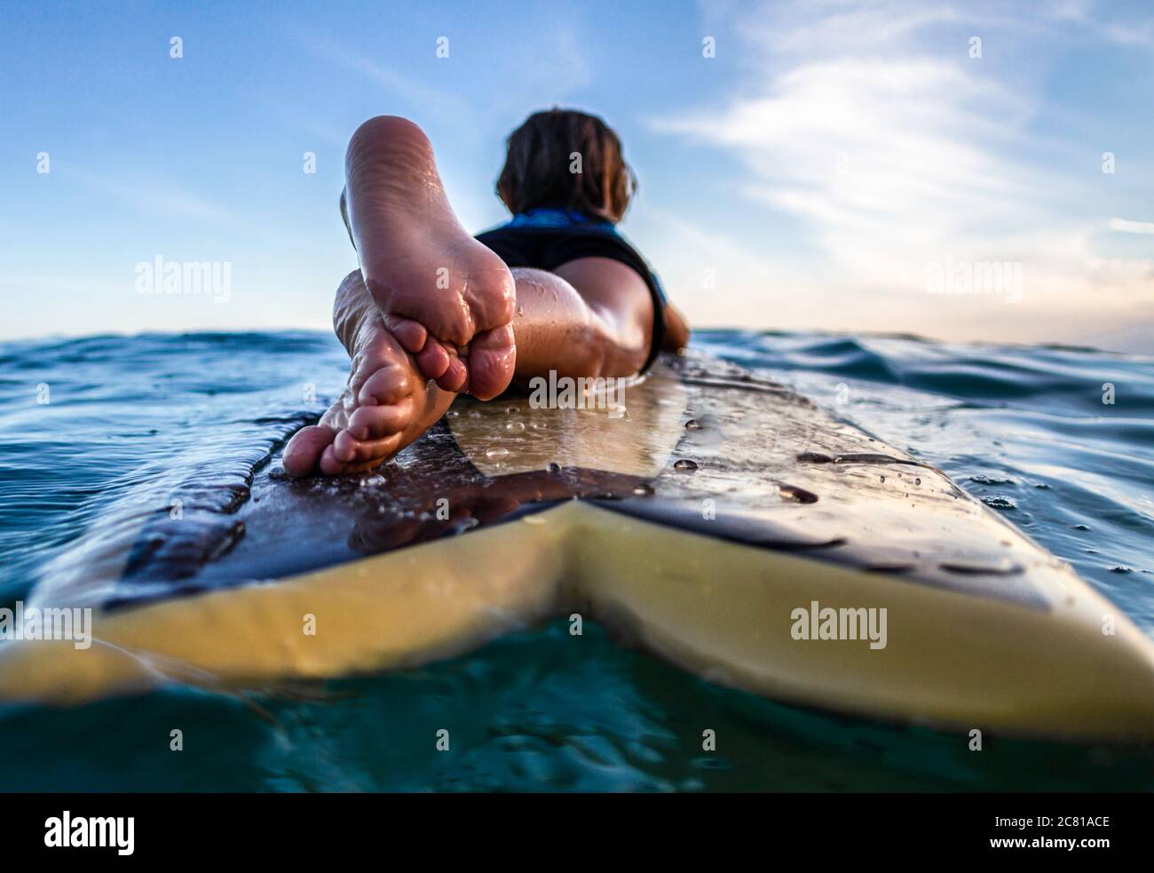 Vista posteriore e primo piano di un 3 anni surfista su tavola di legno Foto Stock