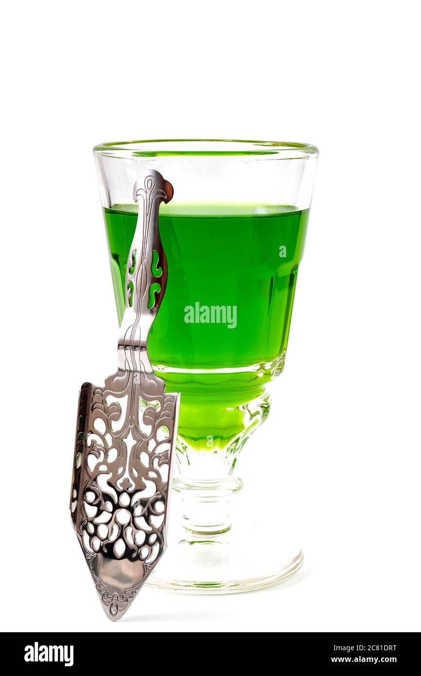 Bevanda alcolica, stimolante creativo e stile di vita bohémien tema con bicchiere di assenzio verde e cucchiaio in acciaio inossidabile isolato sulla parte posteriore bianca Foto Stock