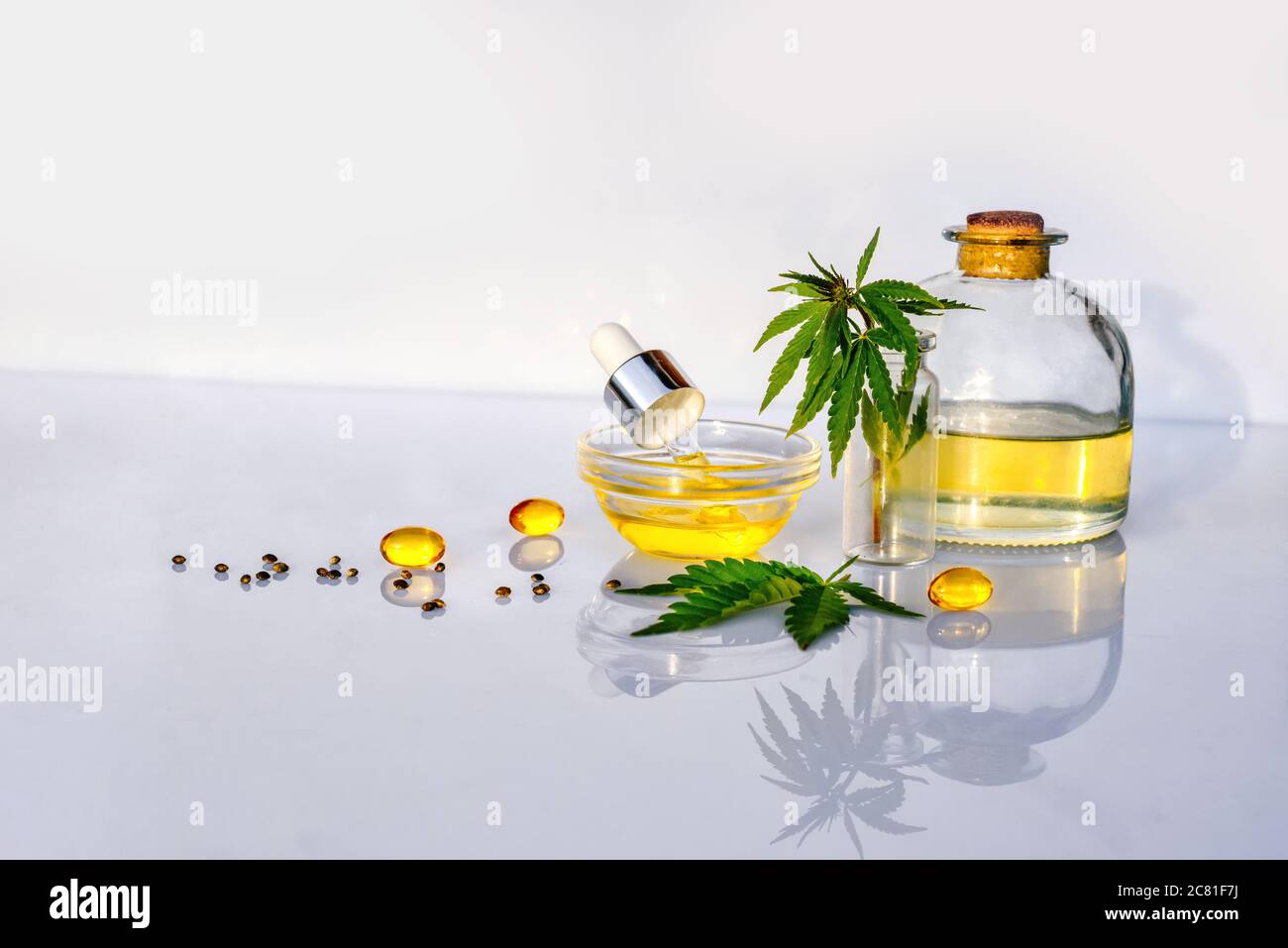 Bottiglia di vetro con olio CBD, tintura THC e foglie di canapa su laboratorio di fondo bianco Foto Stock