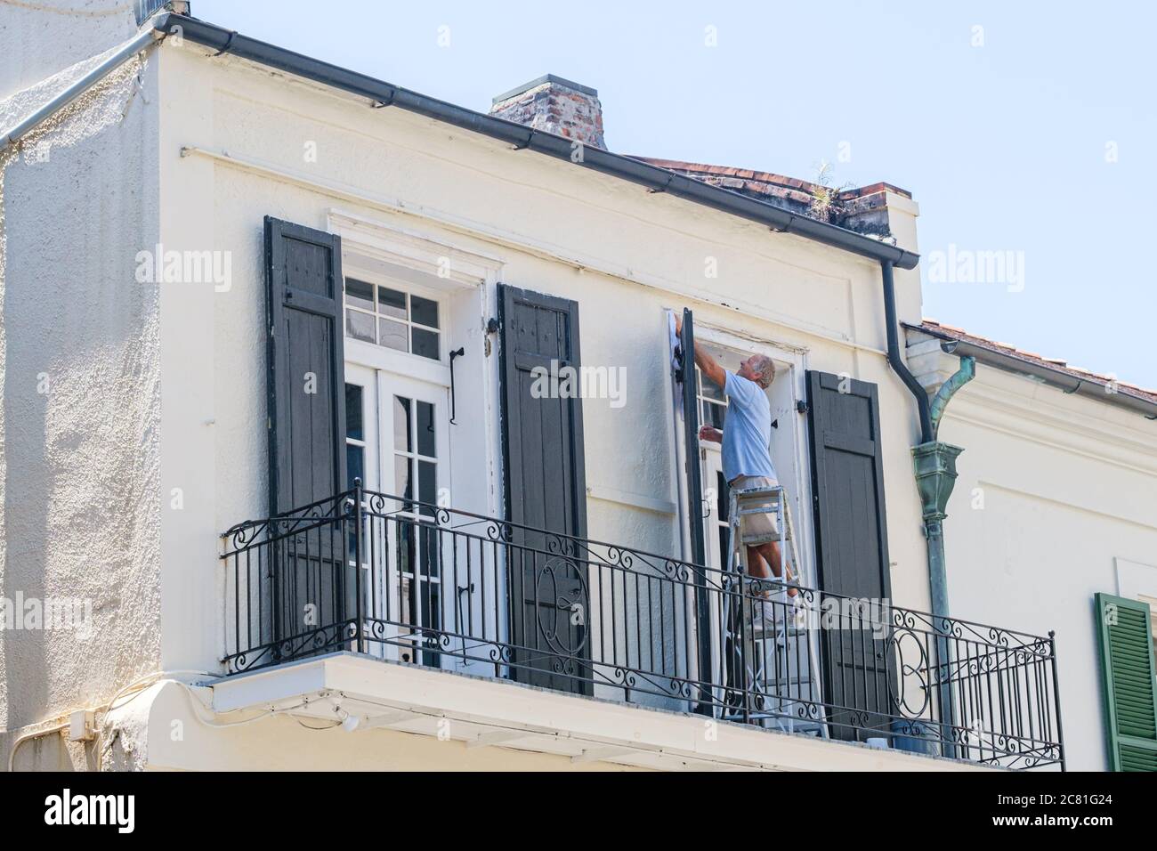 New Orleans, Louisiana/USA - 17/07/2020: La struttura delle finestre per la pulizia dell'uomo si trova fuori dall'edificio storico del quartiere francese Foto Stock
