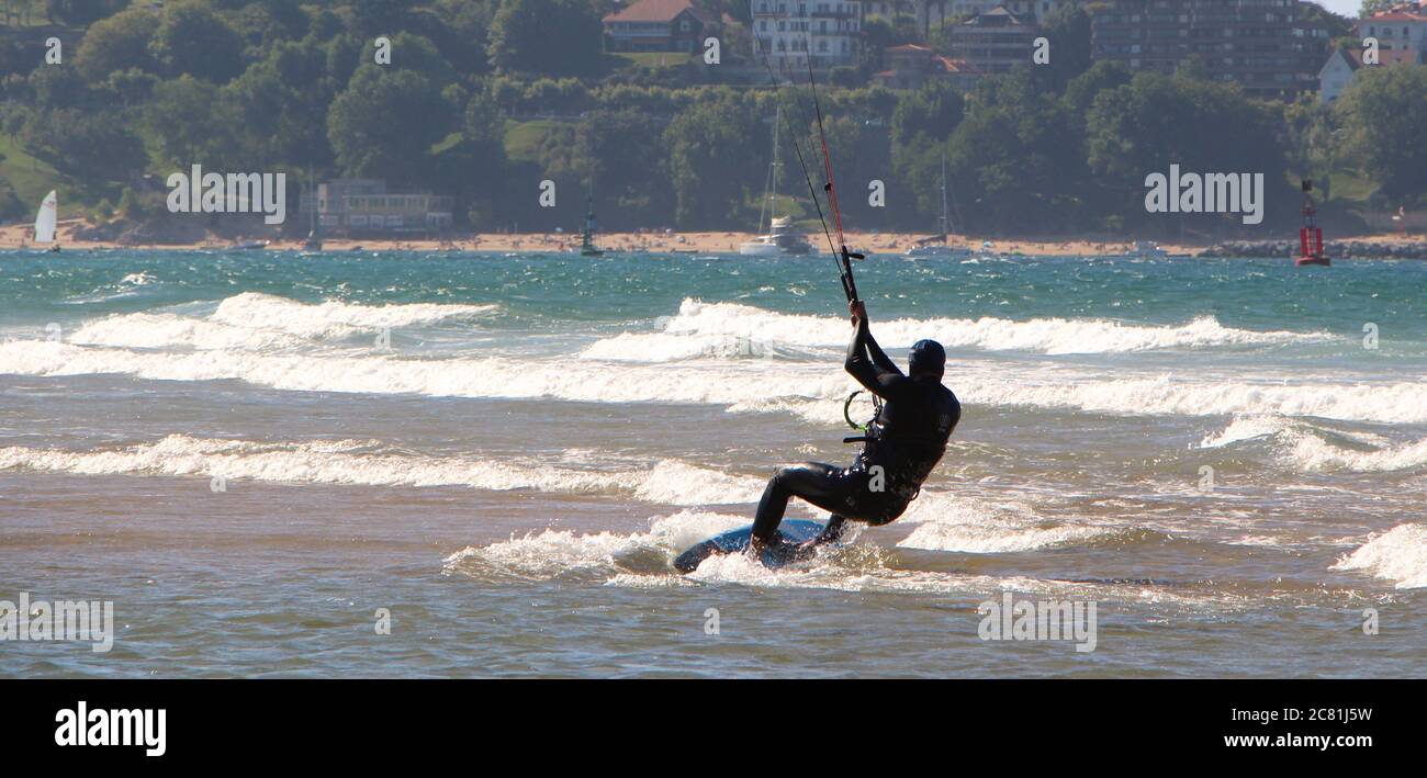 Kitesurf o kiteboarding dalla spiaggia di Somo in un pomeriggio ventoso di sole Santander Cantabria Spagna Estate Foto Stock