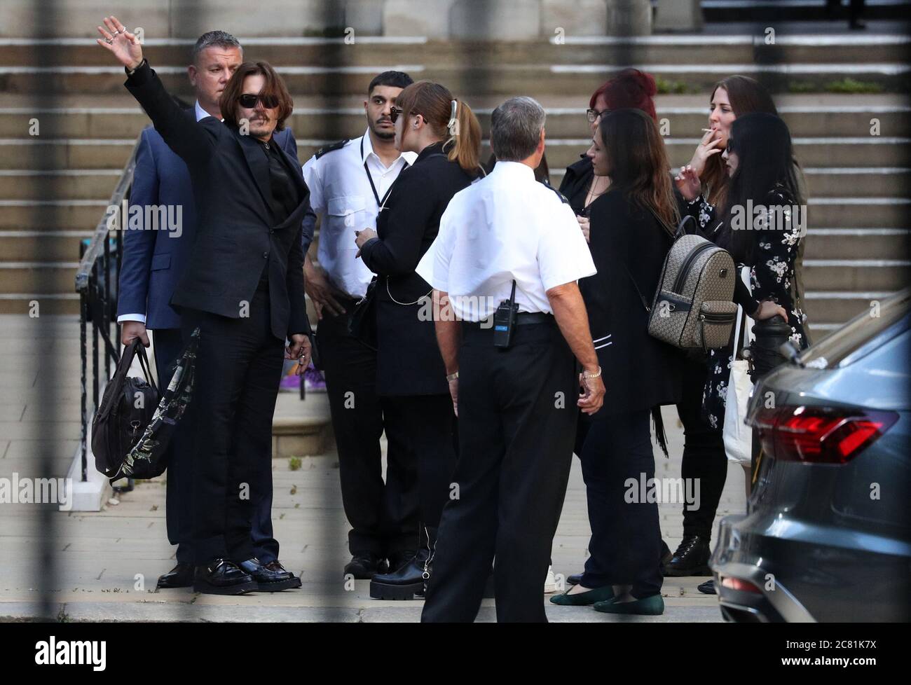 L'attore Johnny Depp (a sinistra) ondeggia nella direzione di fotografie e persone per strada dopo aver incontrato un gruppo di tifosi nel quartiere di corte prima di lasciare l'High Court a Londra in seguito ad un'audizione nella sua causa contro gli editori del Sun e il suo direttore esecutivo, DaN Wootton. Foto Stock