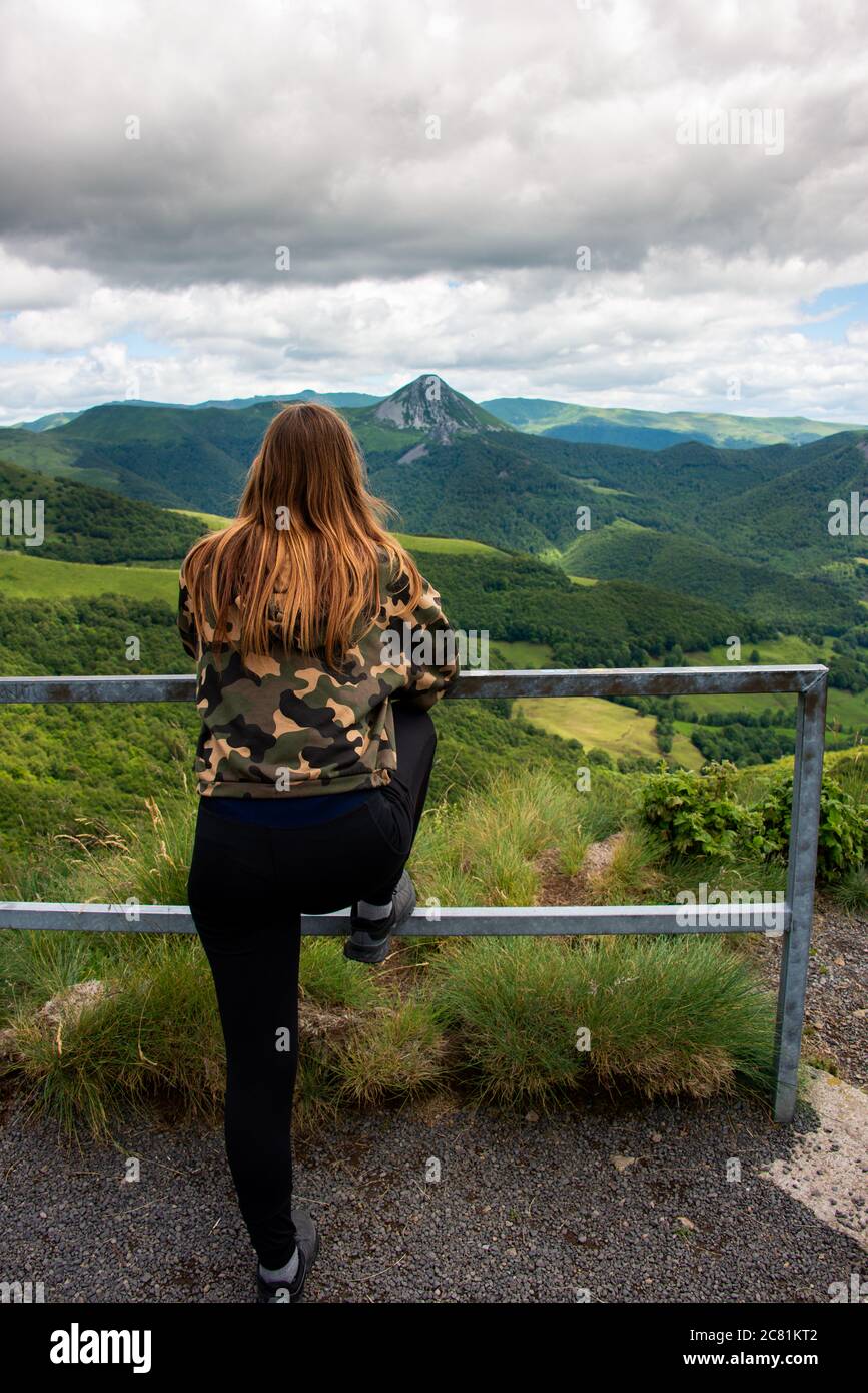 Giovane donna che si allunga guardando la vista dei vecchi vulcani, vacanze avventura, auvergne ,Francia . Foto Stock