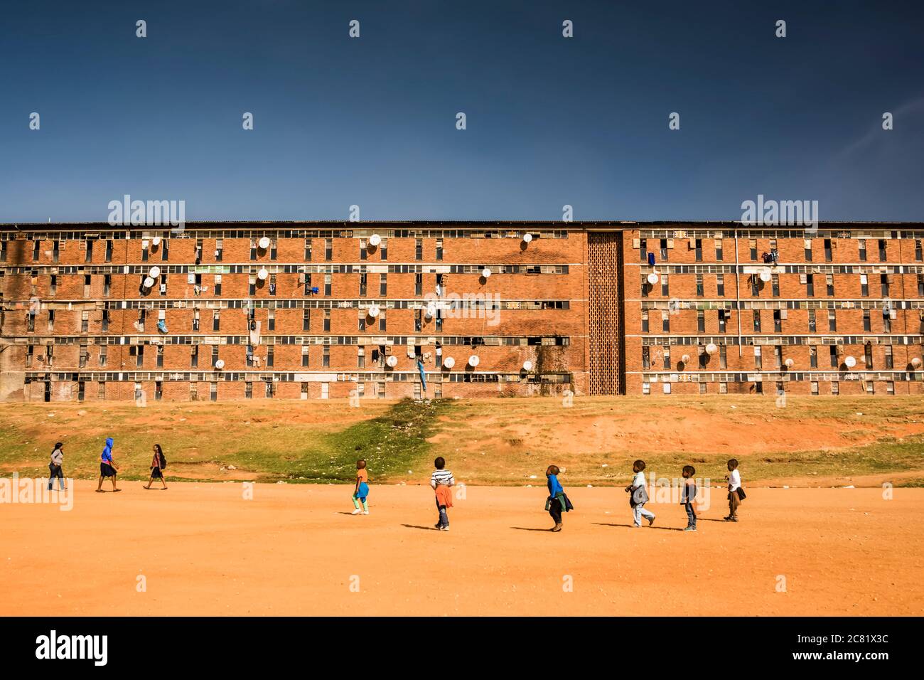 Bambini che giocano fuori di un ostello lavoratori in Alexandra Township; Johannesburg, Gauteng, Sudafrica Foto Stock