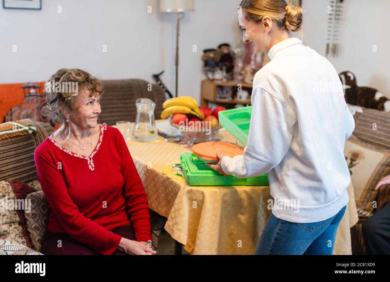 Volontariato che serve un pasto a una donna anziana in programma di vita assistita Foto Stock