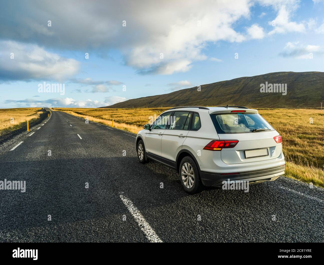 Un veicolo è parcheggiato sul lato di una strada asfaltata con una vista del vasto paesaggio nel sud dell'Islanda; Kjosarhreppur, regione meridionale, Islanda Foto Stock