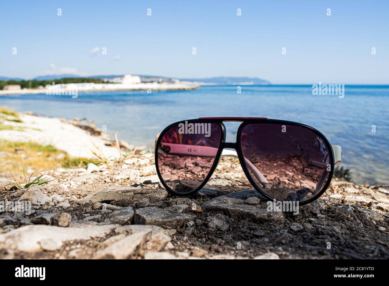 Bella vacanza estiva. Gli occhiali da sole sono sdraiati sulla spiaggia, in estate, con il sole, contro il mare della città di Gelendzhik Foto Stock