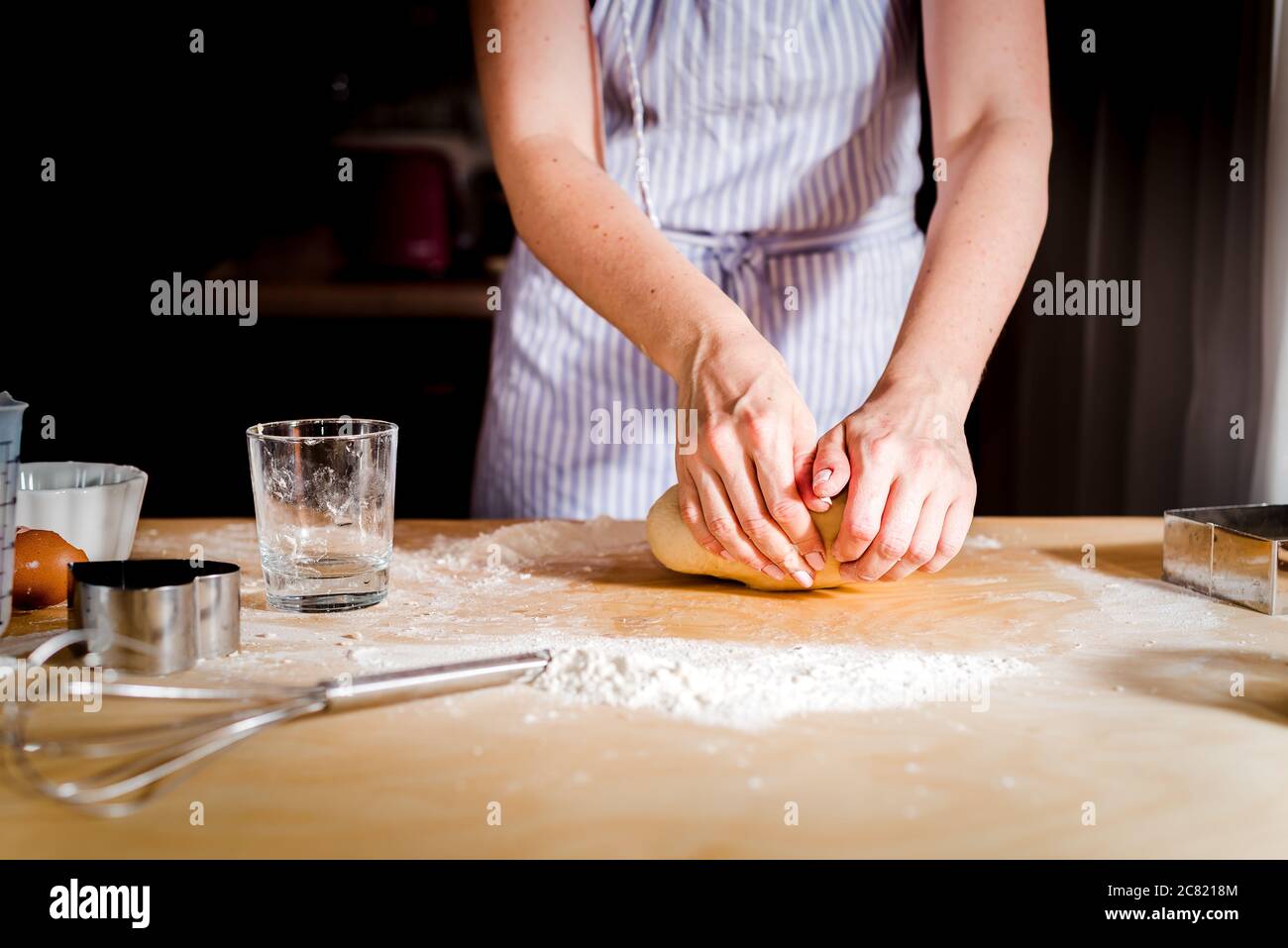 le mani delle donne impastano l'impasto sul tavolo, accessori da cucina Foto Stock