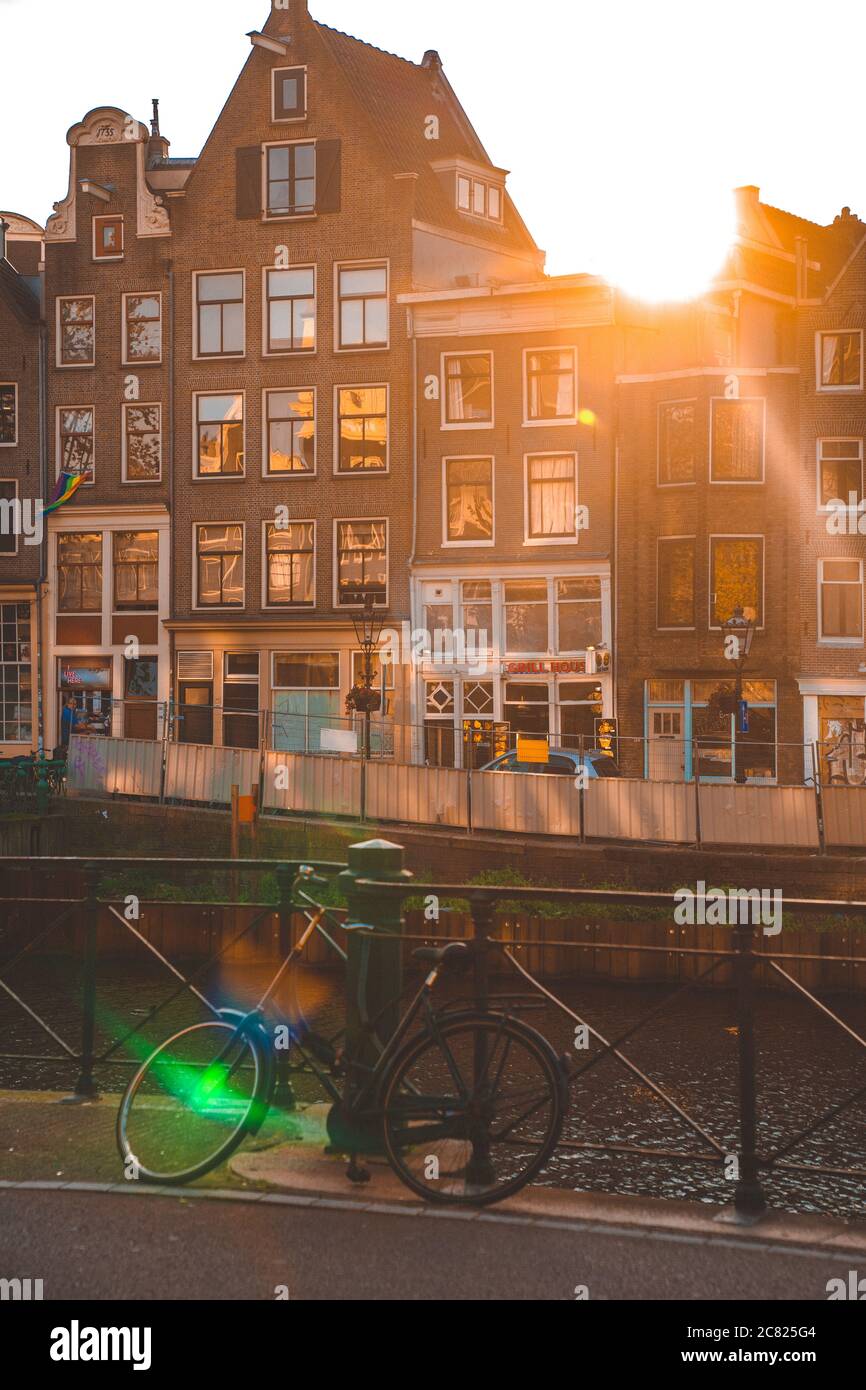 Tiro verticale di una bicicletta sul ponte canale e. il sole splende sopra i tetti Foto Stock