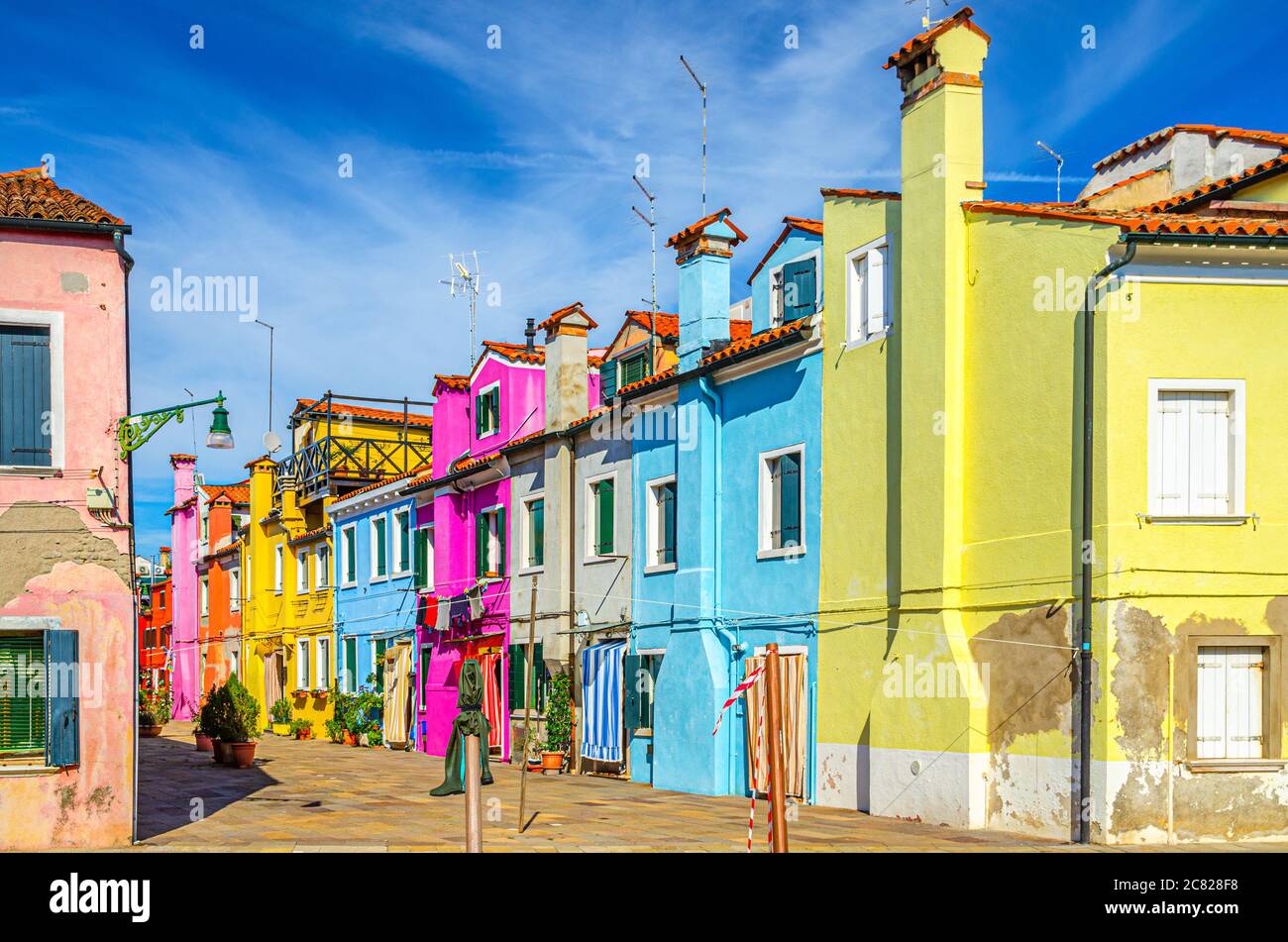 Case colorate dell'isola di Burano. Edifici multicolore in stradina, cielo blu in piena estate, provincia di Venezia, Regione Veneto, Italia settentrionale. Burano cartolina Foto Stock