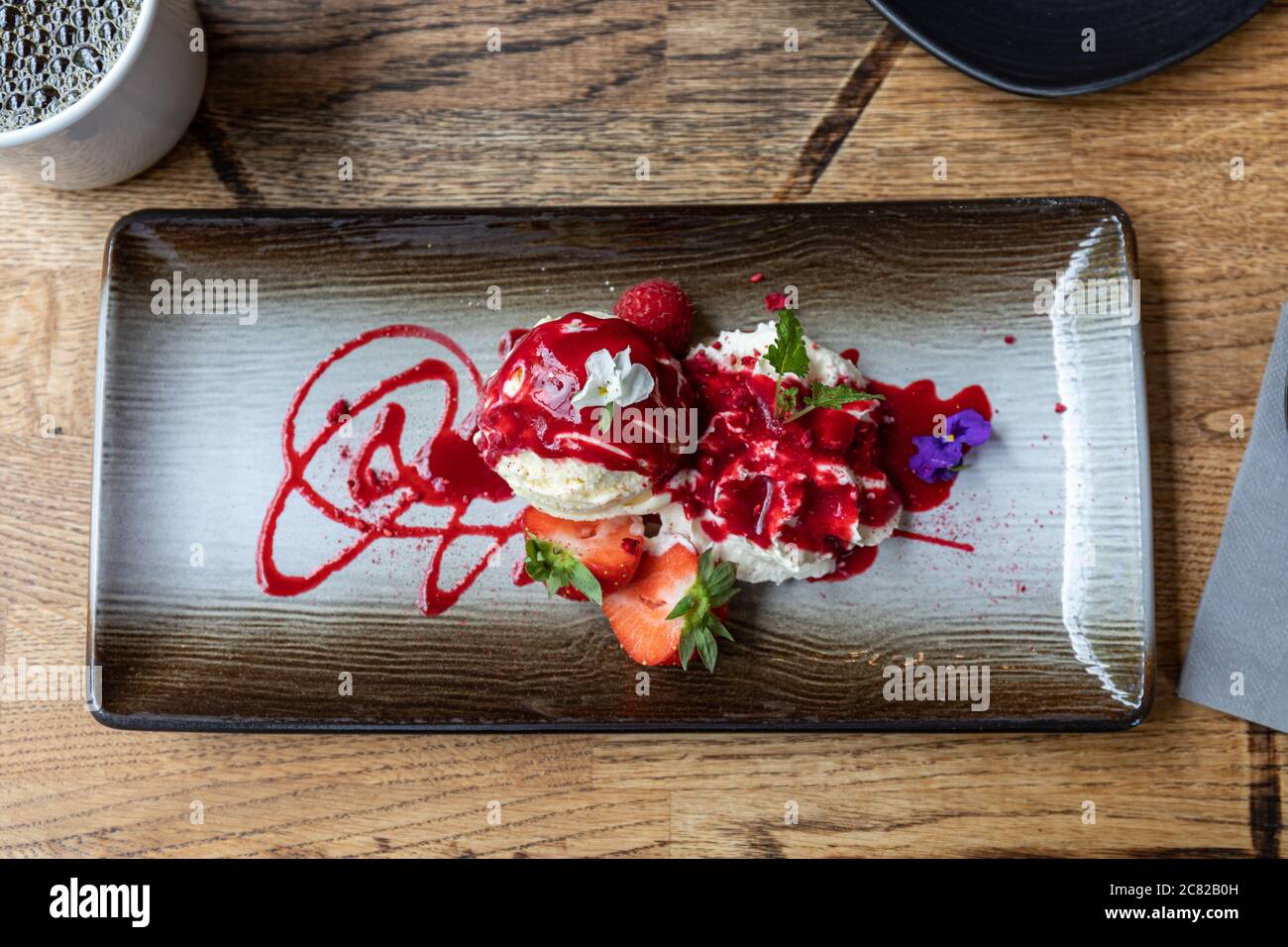 Gelato alla vaniglia con panna montata, fragole e salsa di lamponi Foto Stock