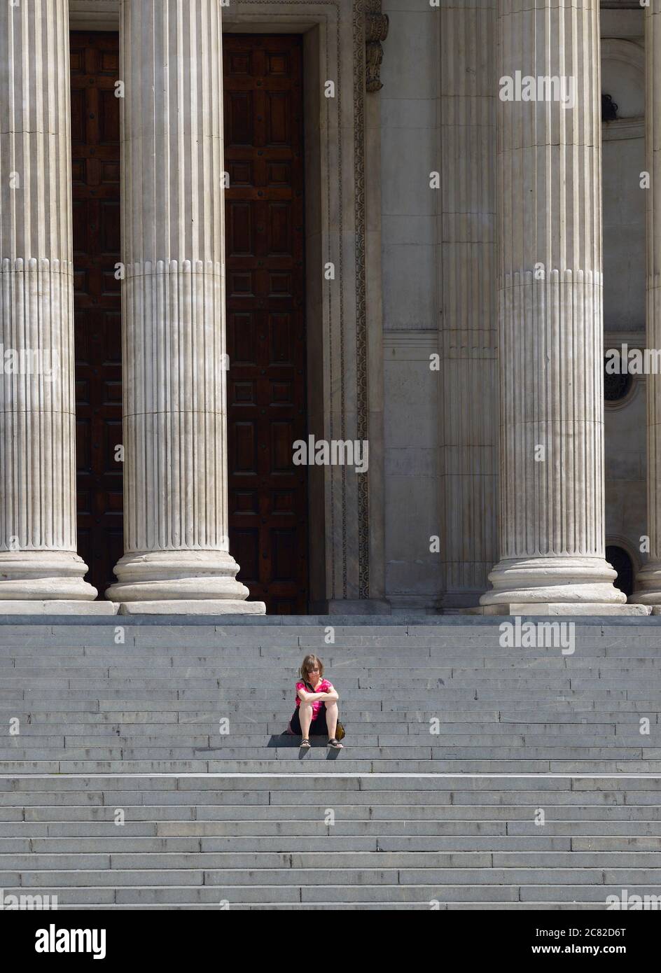Londra, Inghilterra, Regno Unito. Donna seduta da sola sui gradini della Cattedrale di San Paolo durante l'epidemia di COVID-19, luglio 2020 Foto Stock