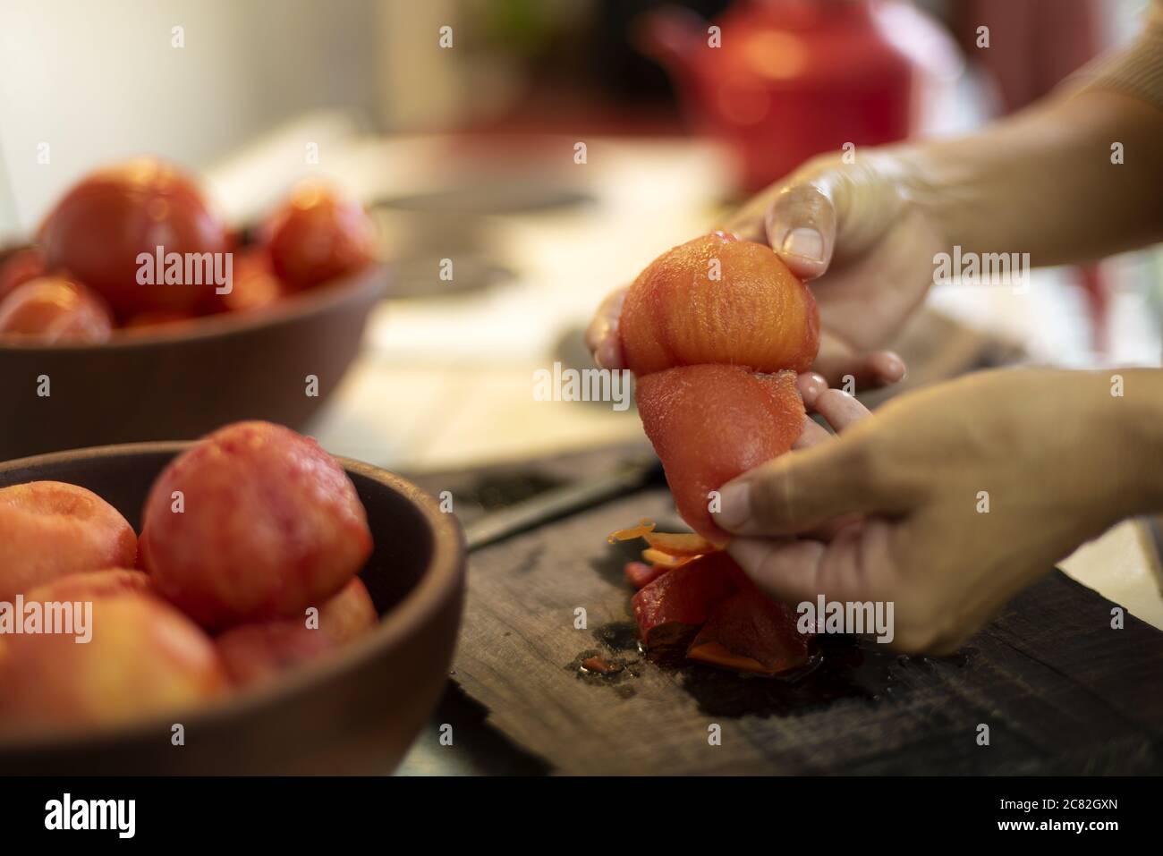 Colpo di primo piano di una femmina che spellano un pomodoro con un sfondo sfocato Foto Stock