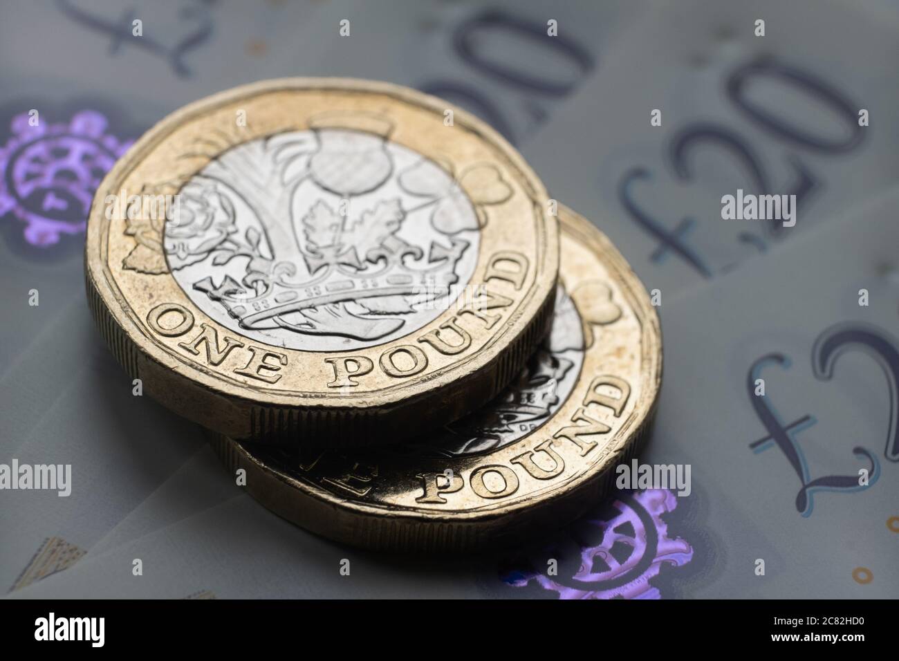 Monete nuove da una libbra poste sopra le nuove banconote inglesi in sterline. Primo piano con messa a fuoco selettiva. Il fuoco principale è sulle monete. Foto Stock