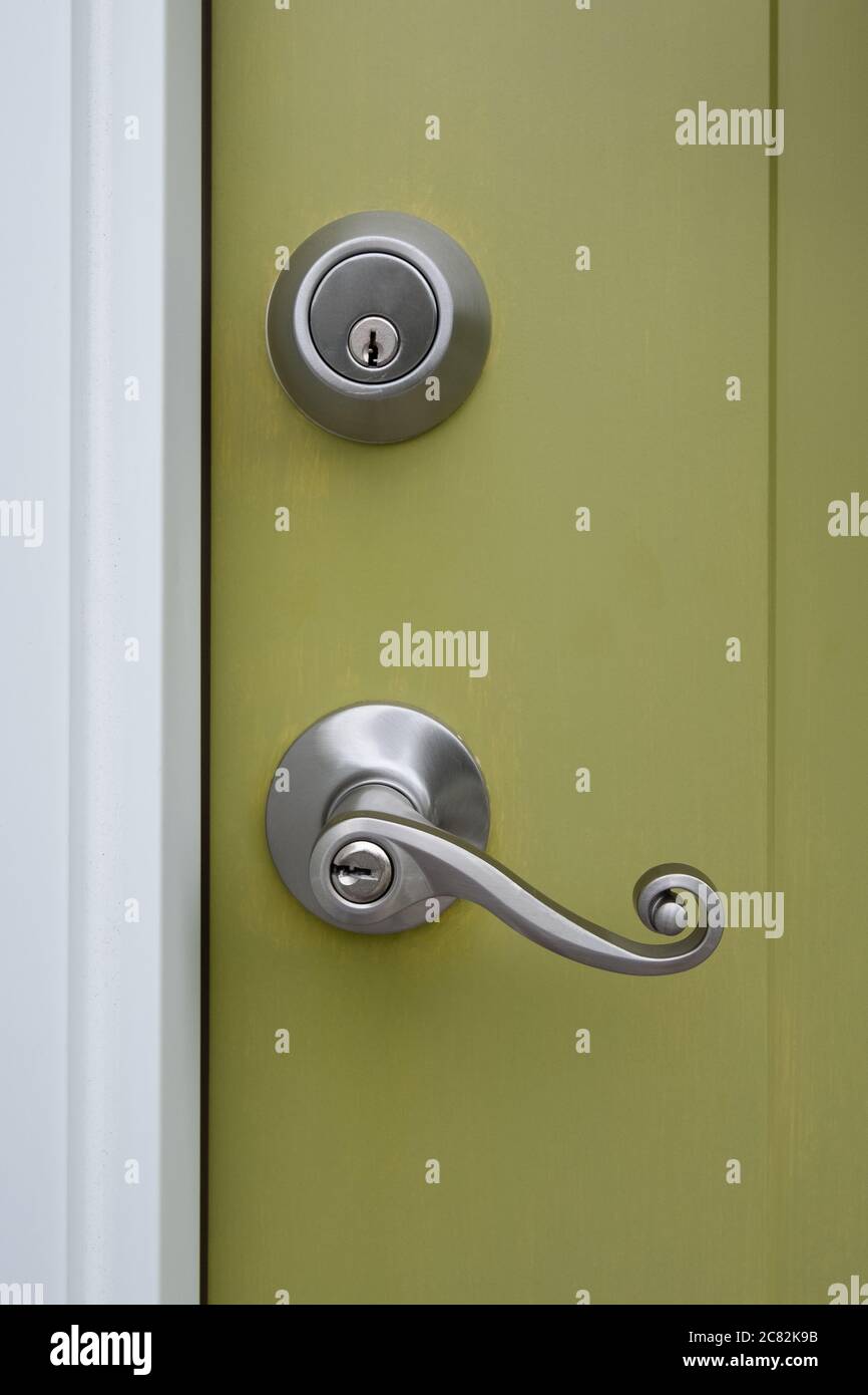 Fotografia di una porta anteriore a casa con un elegante pomello per porta a peltro e un set di bulloni ad effetto globale Foto Stock