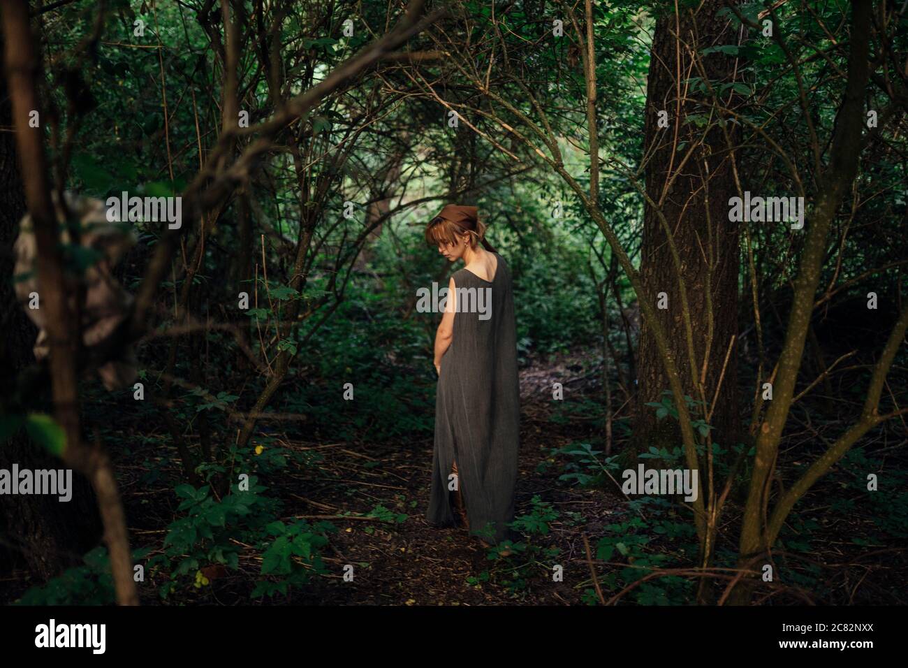 donna in piedi indietro nella foresta Foto Stock