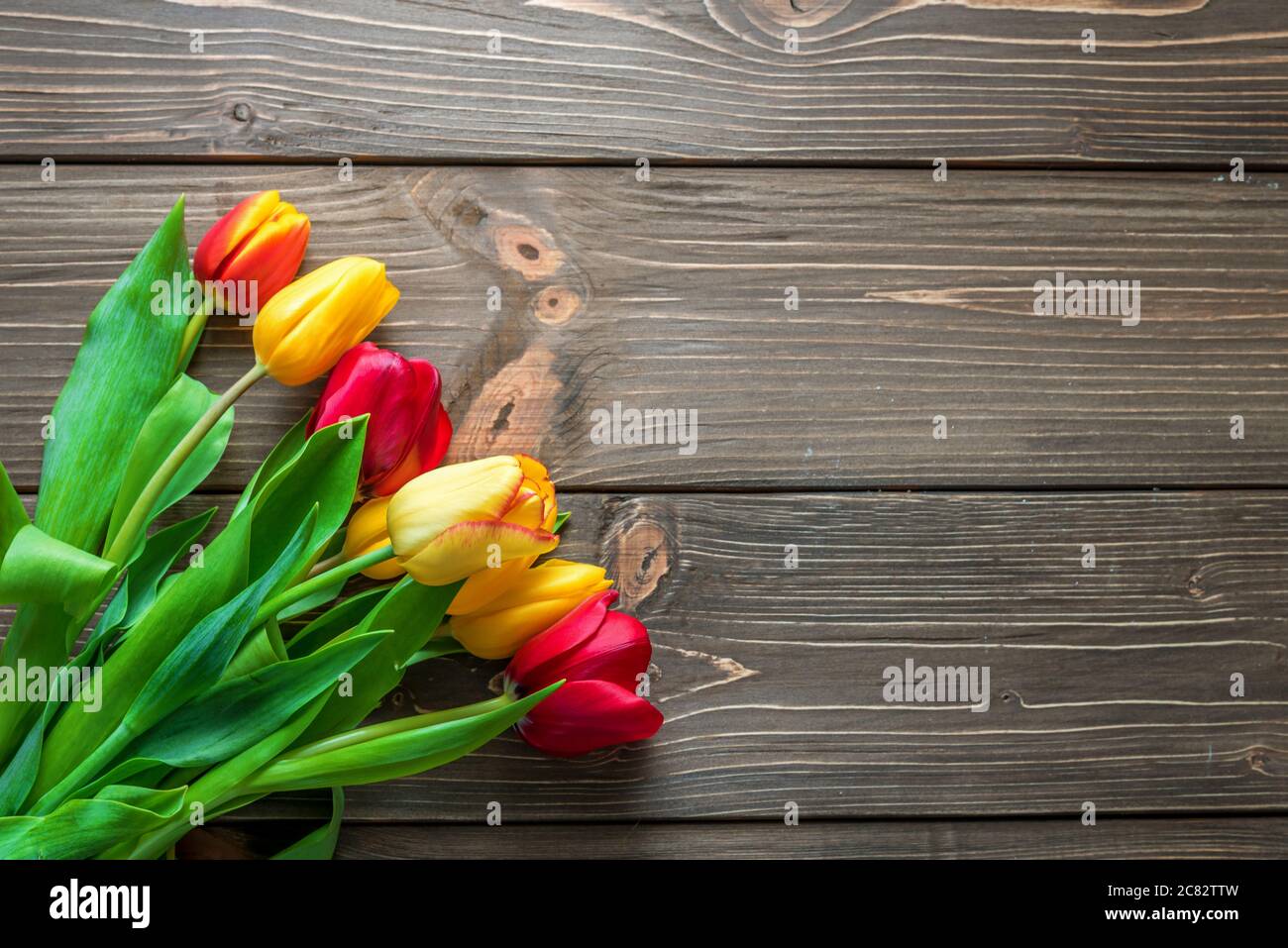 Bouquet di tulipani in una borsa della spesa di carta su sfondo in legno, concetto di sconti e vendite per la festa della donna, la festa della mamma o pasqua Foto Stock