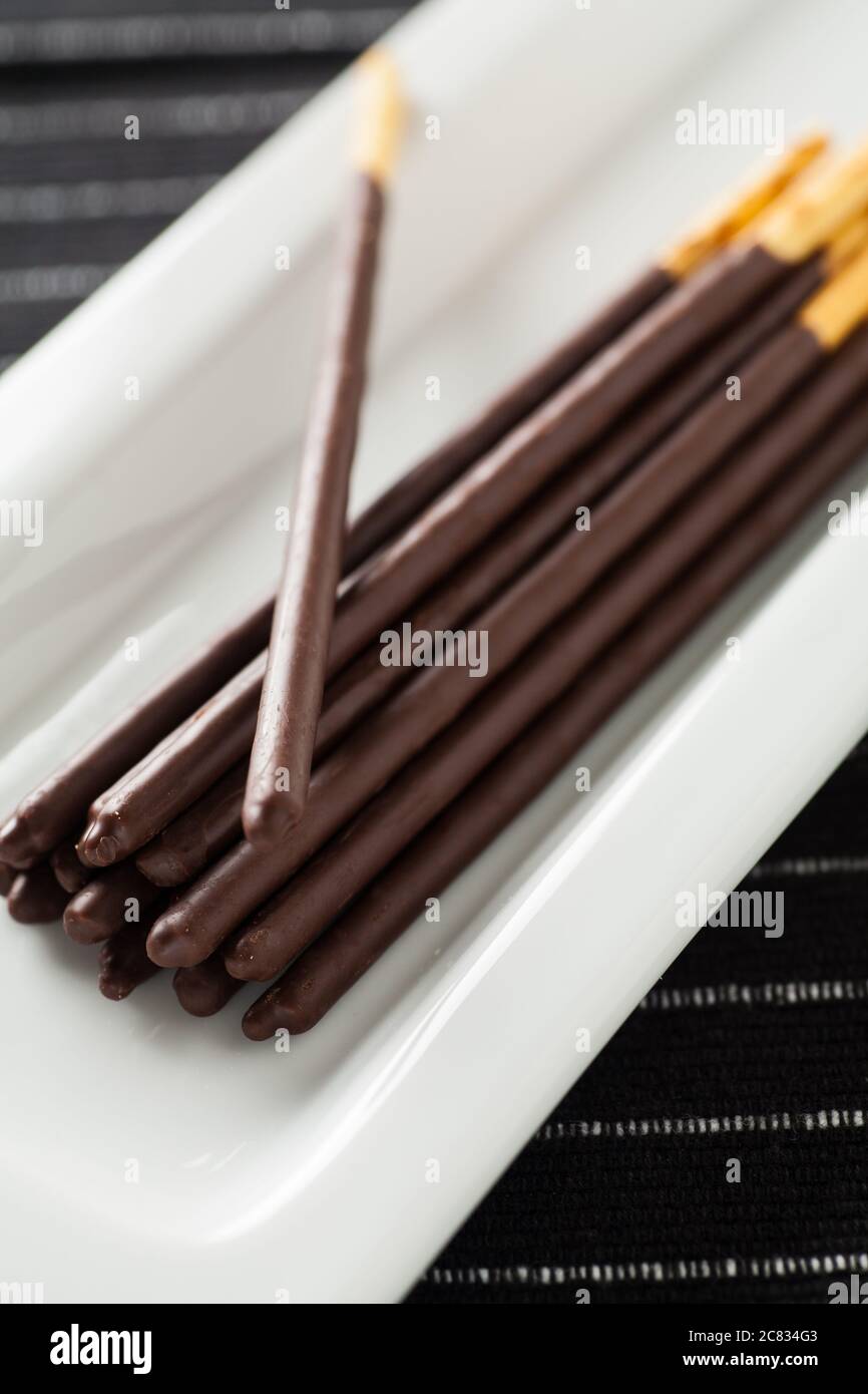 Immagine verticale di bastoncini di cioccolato posati su un lungo piastra bianca Foto Stock
