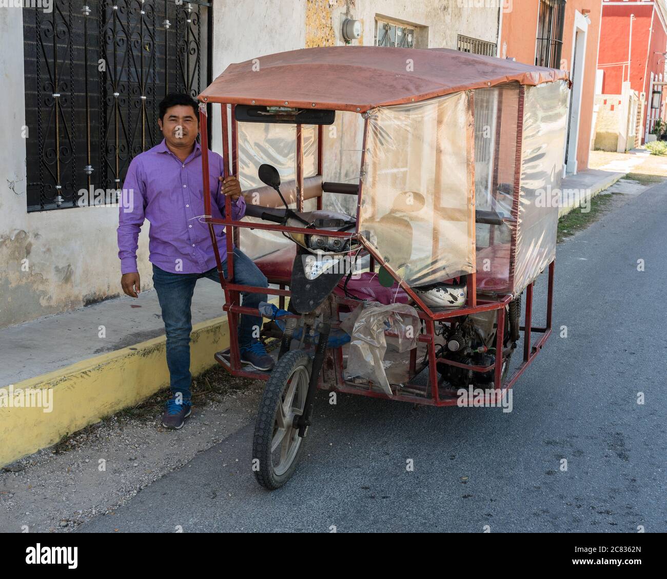 Un pilota si pone accanto al suo mototaxi a tre ruote nella città di Nolo, Yucatan, Messico. La moto è stata tagliata a metà e la metà posteriore con il moto Foto Stock