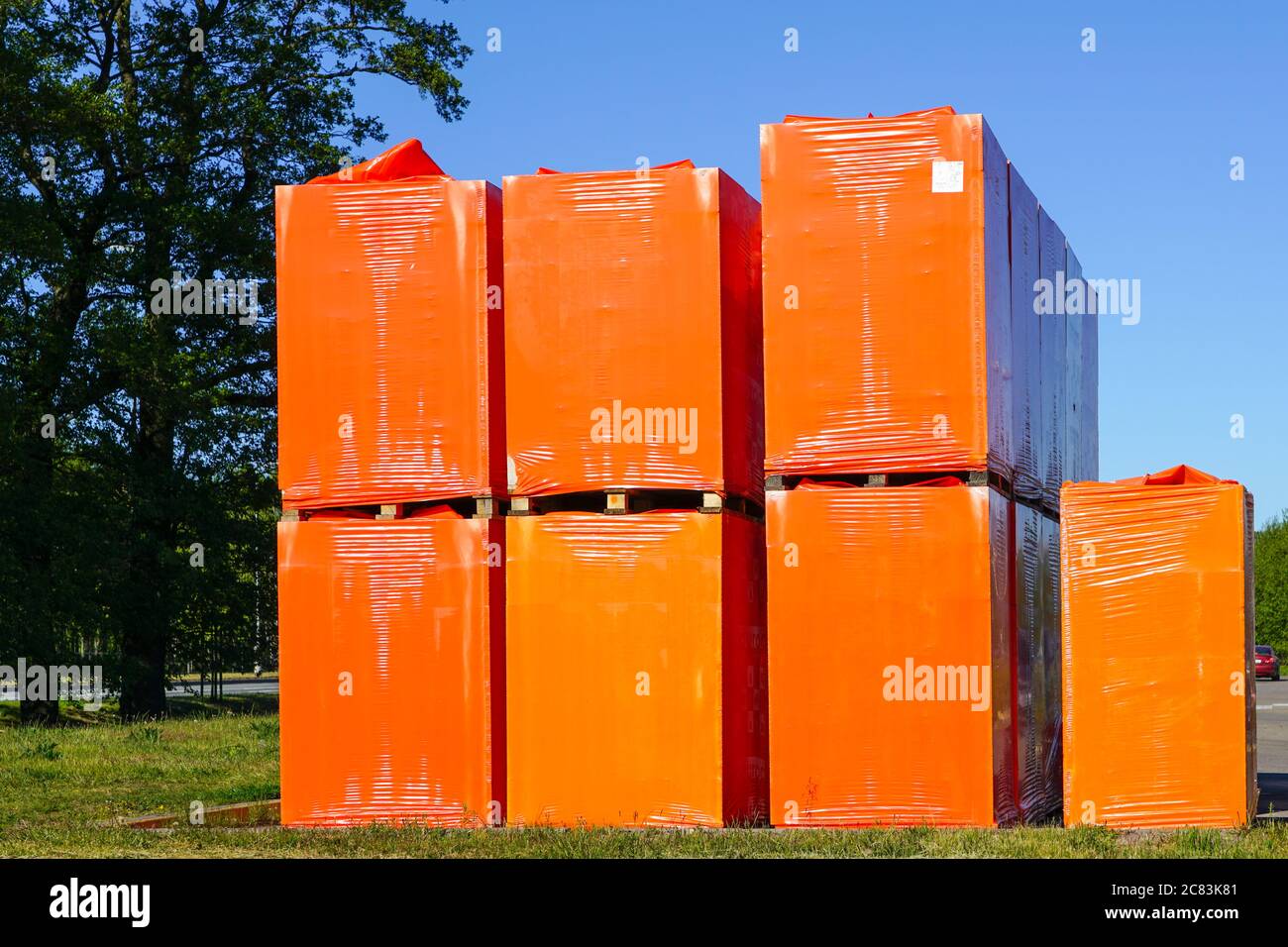 materiali da costruzione avvolti in pellicola arancione e posti su pallet sotto il cielo aperto Foto Stock