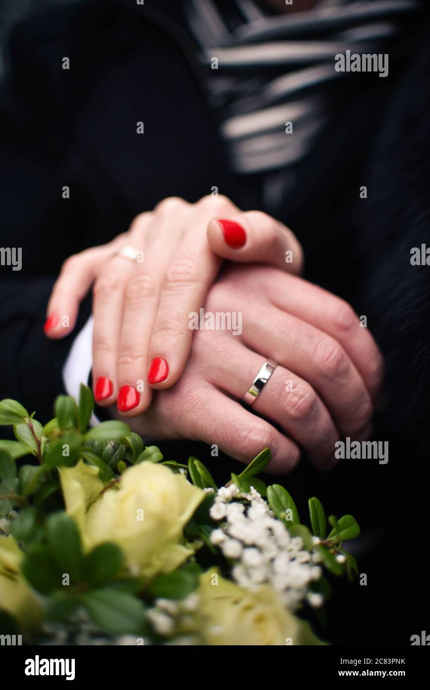 Mani nuove con manicure rossa con anelli dorati. Foto Stock
