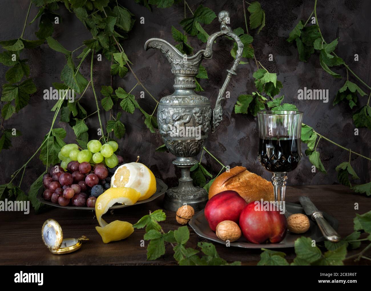 Ancora vita in stile medievale con antiche caraffe di peltro e calice di vetro ripieno di vino rosso, nonché noci, uva, limone e nettarine sono su Foto Stock