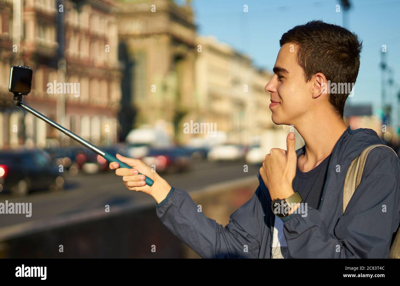 il giovane uomo con un telefono è sulla strada di una grande città e pollici su, blogger comunica con i popoli Foto Stock