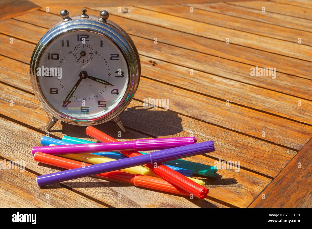 Sveglia e matite di feltro-punta per simbolizzare il tempo di tornare a scuola Foto Stock