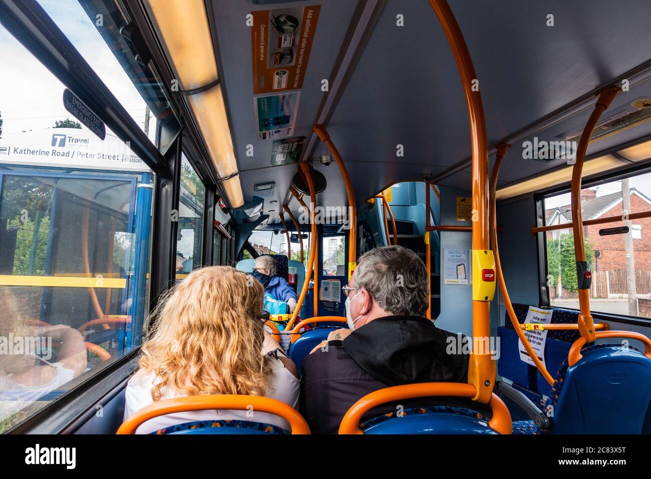 Una coppia che indossa maschere di faccia seduto su un viaggio in autobus seduto a parte durante le regole sociali di distanza Foto Stock
