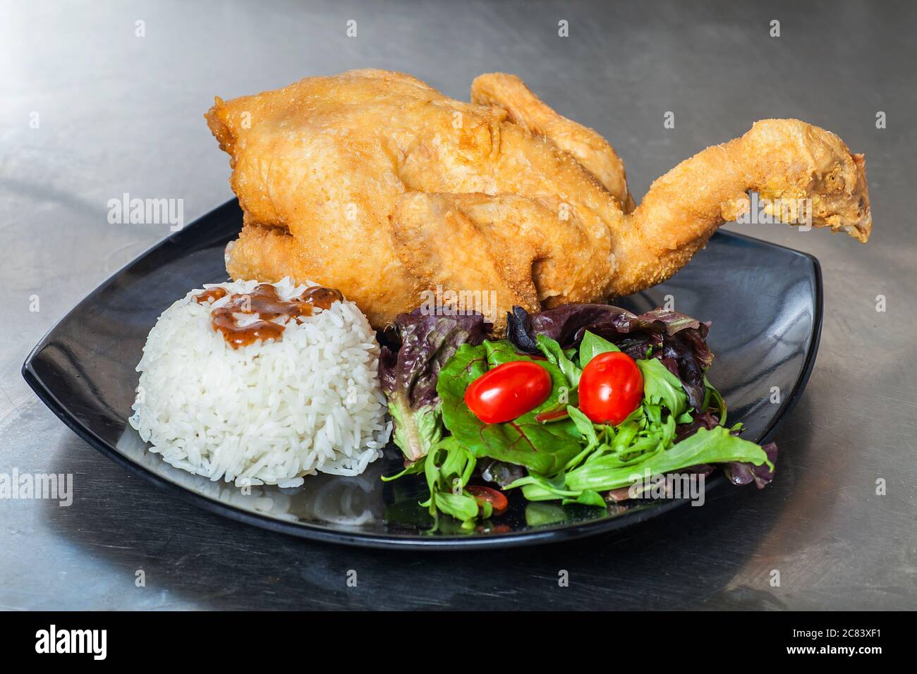 Presentazione di un piatto di cibo occidentale consiste di riso, insalate e pollo intero primavera. Foto Stock