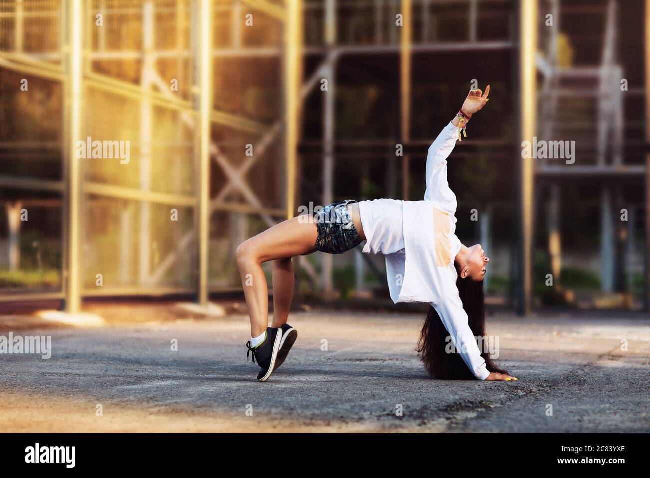 La ragazza danza su una piattaforma di strada nella sera soleggiata estiva Foto Stock