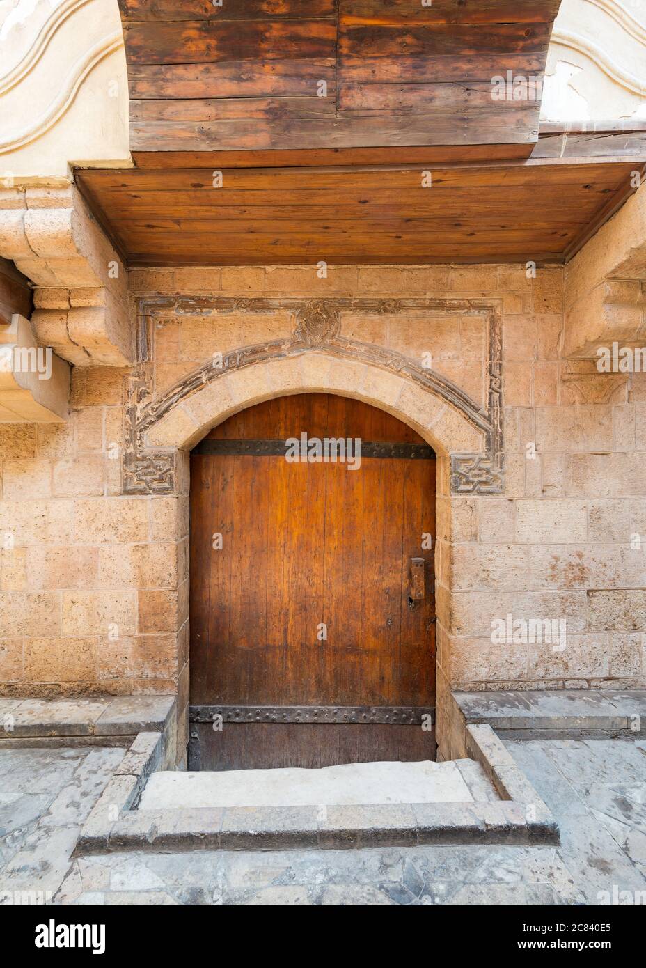 Esterno di una casa in pietra con pareti stagne e porta in legno ad arco, nella città vecchia Foto Stock