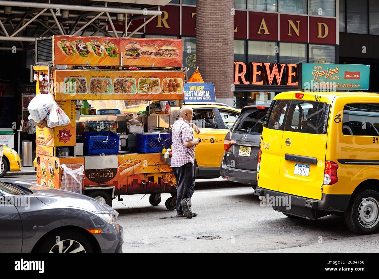 New York, USA - 28 giugno 2018: L'uomo con un carrello di cibo attende in ingorgo sulla strada di Manhattan. Foto Stock