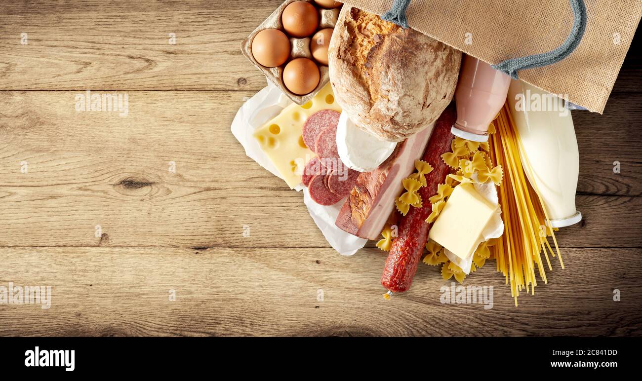 Borsa con pasta italiana secca e un assortimento di latticini, uova, salumi e salsiccia piccante su fondo rustico di legno con copyspac Foto Stock