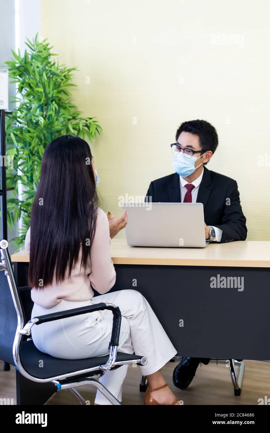 Ritratto di consulente asiatico di affari che dà consiglio al cliente circa la situazione di prestito finanziario in ufficio bancario. Nuovo business a distanza sociale normale per ba Foto Stock