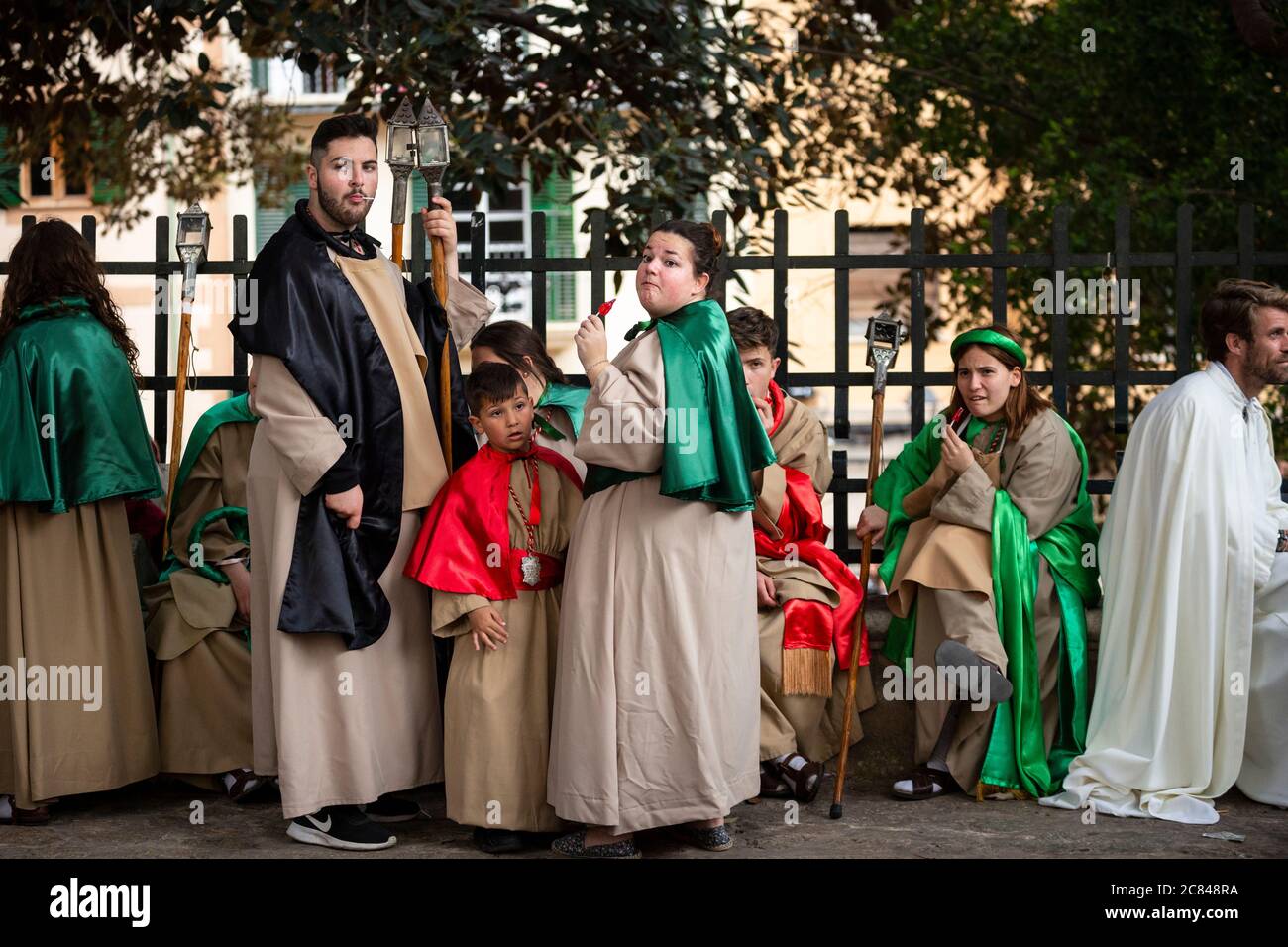 Gruppo di persone vestite di garb religioso succhiano sui lollipop durante la parata pasquale a Palma, Maiorca Foto Stock