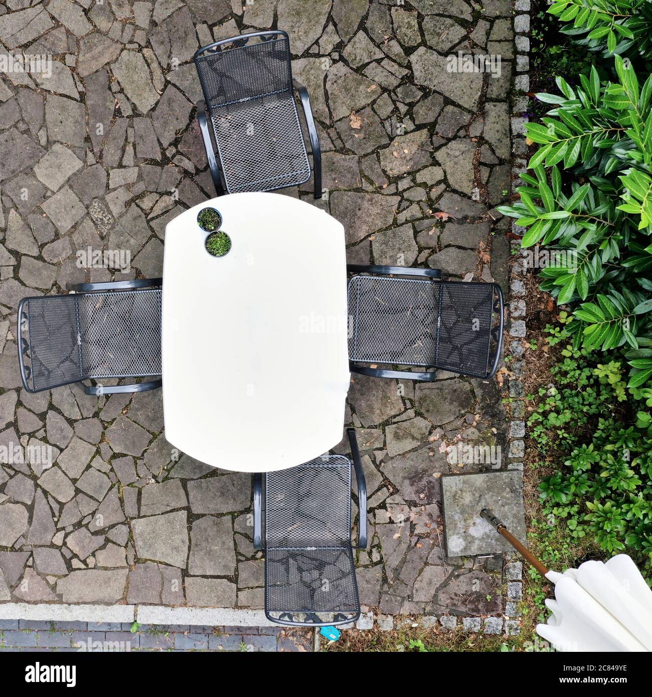 Vista aerea verticale di un tavolo da giardino e sedie da giardino in rete metallica su una terrazza in ardesia Foto Stock