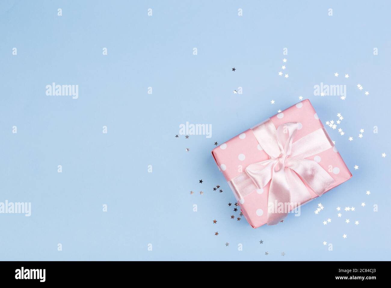 Confezione regalo o regalo e stelle confetti su un tavolo blu dall'alto. Composizione piatta per compleanno, giorno delle madri o matrimonio. Foto Stock