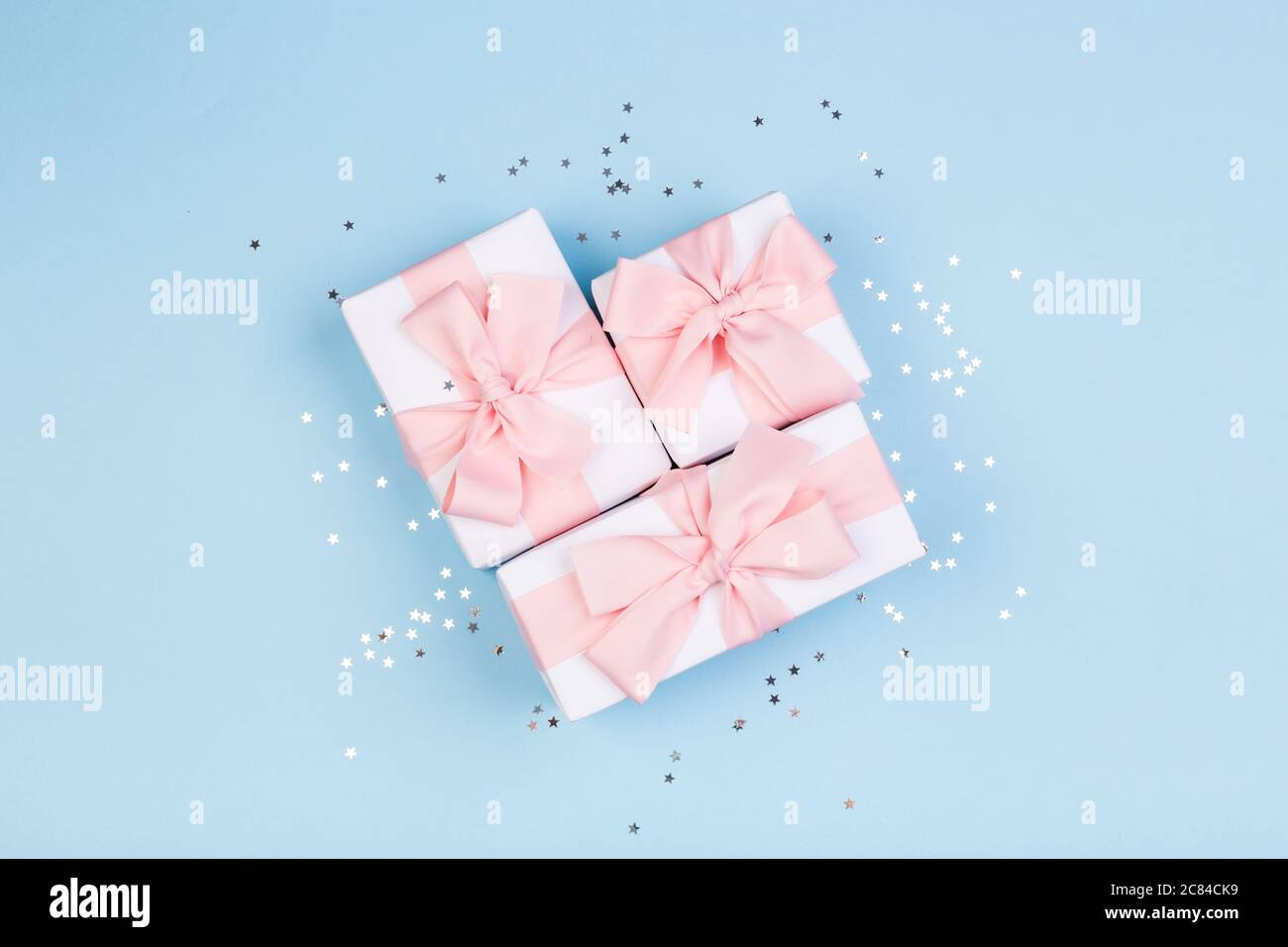 Confezione regalo o regalo e stelle confetti su un tavolo blu dall'alto. Composizione piatta per compleanno, giorno delle madri o matrimonio. Foto Stock