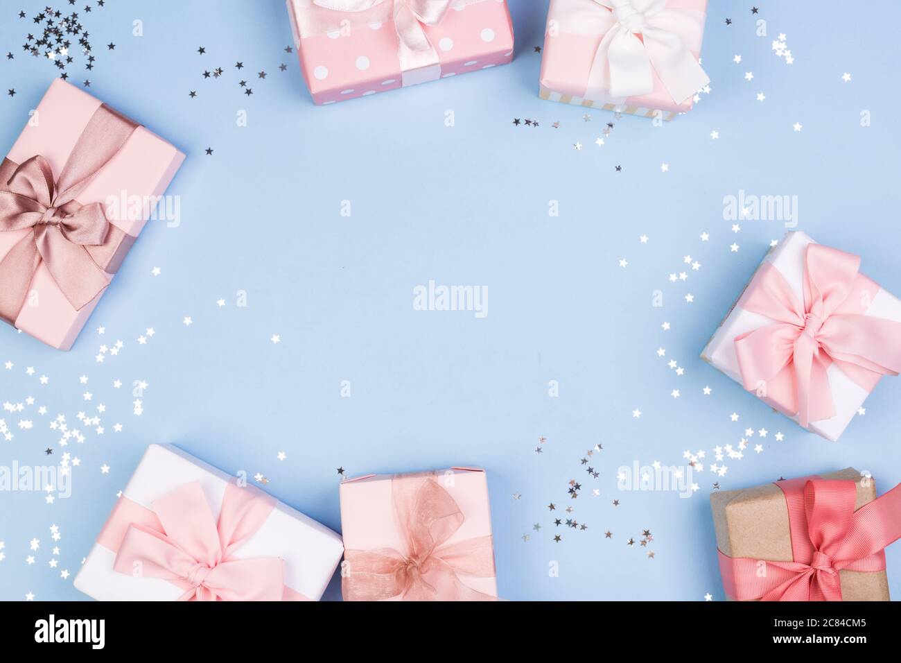 Confezione regalo o regalo e stelle confetti su un tavolo blu dall'alto. Composizione piatta per compleanno, giorno delle madri o matrimonio. Foto Stock