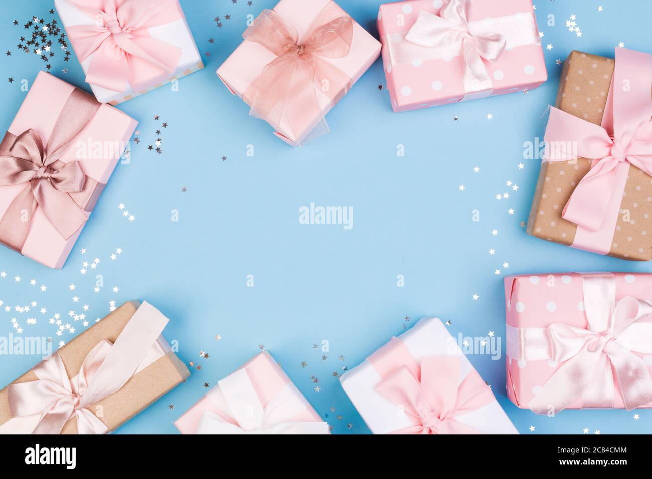 Confezione regalo o regalo e stelle confetti su un tavolo blu dall'alto. Composizione piatta per compleanno, giorno delle madri o matrimonio. Foto Stock