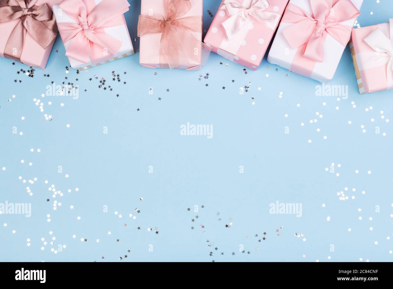 Confezione regalo o regalo e stelle confetti su un tavolo blu dall'alto. Composizione piatta per compleanno, giorno delle madri o matrimonio. Foto Stock