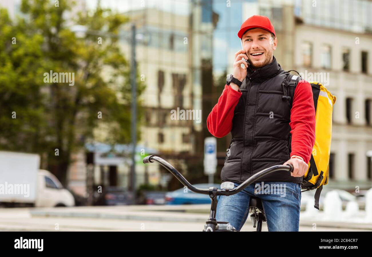 Consegna Guy parlare su cellulare che consegna cibo in città Foto Stock