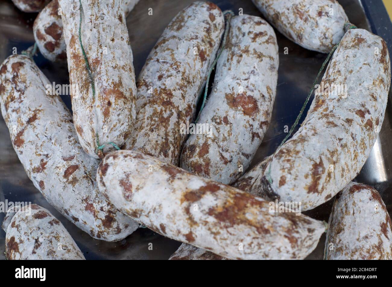 Primo piano di alcuni salametti ticinesi tradizionali (salsiccia di maiale tipica del Canton Ticino) che si trovano in vendita in molti mercati italiani Foto Stock