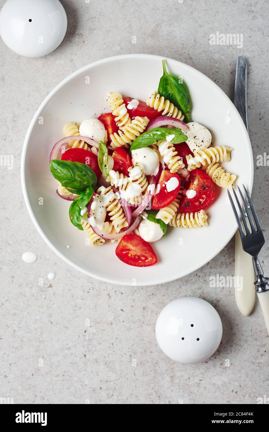 Insalata di pasta con pomodori, mozzarella e foglie di basilico. Foto Stock