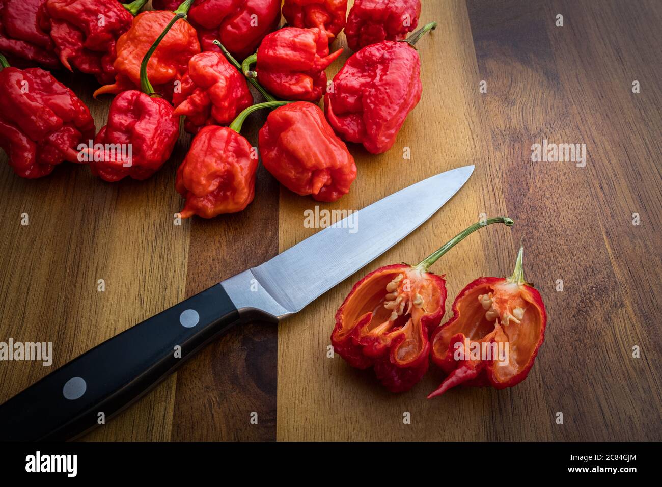 Fotografia di Peperoni di Carolina Reaper su un banco di legno con coltello - i peperoni più caldi nel mondo! Foto Stock