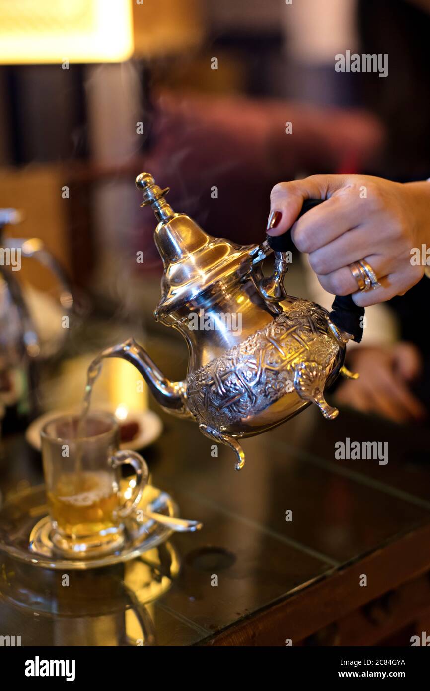 Versare il tè nella tazza da tè su un tavolo di legno Foto Stock