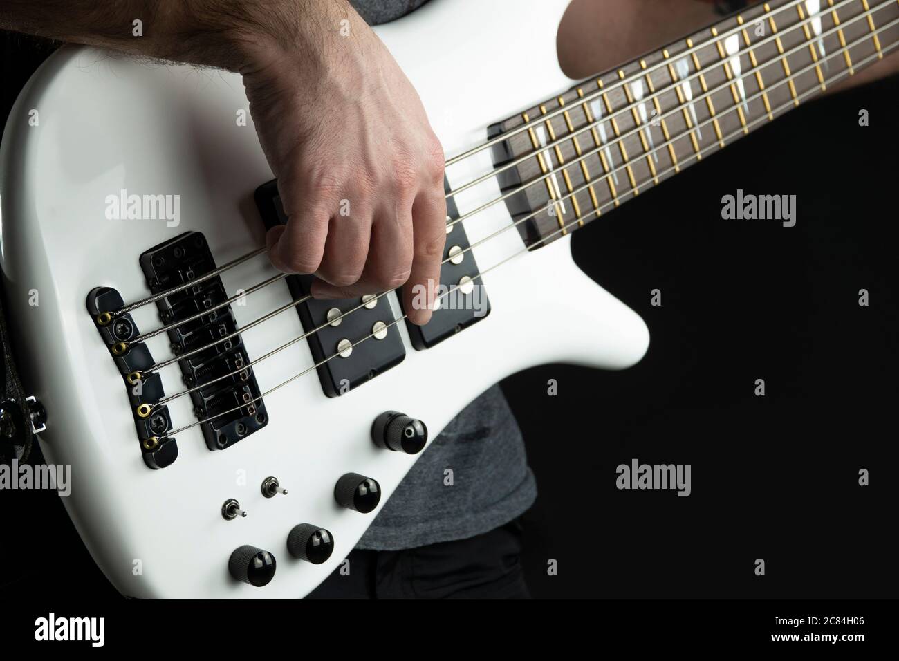 il chitarrista basso suona la chitarra elettrica basso con finitura bianca lucida, musica dal vivo. Foto Stock